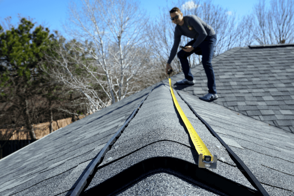Roofer on roof showing how to measure roof for shingles